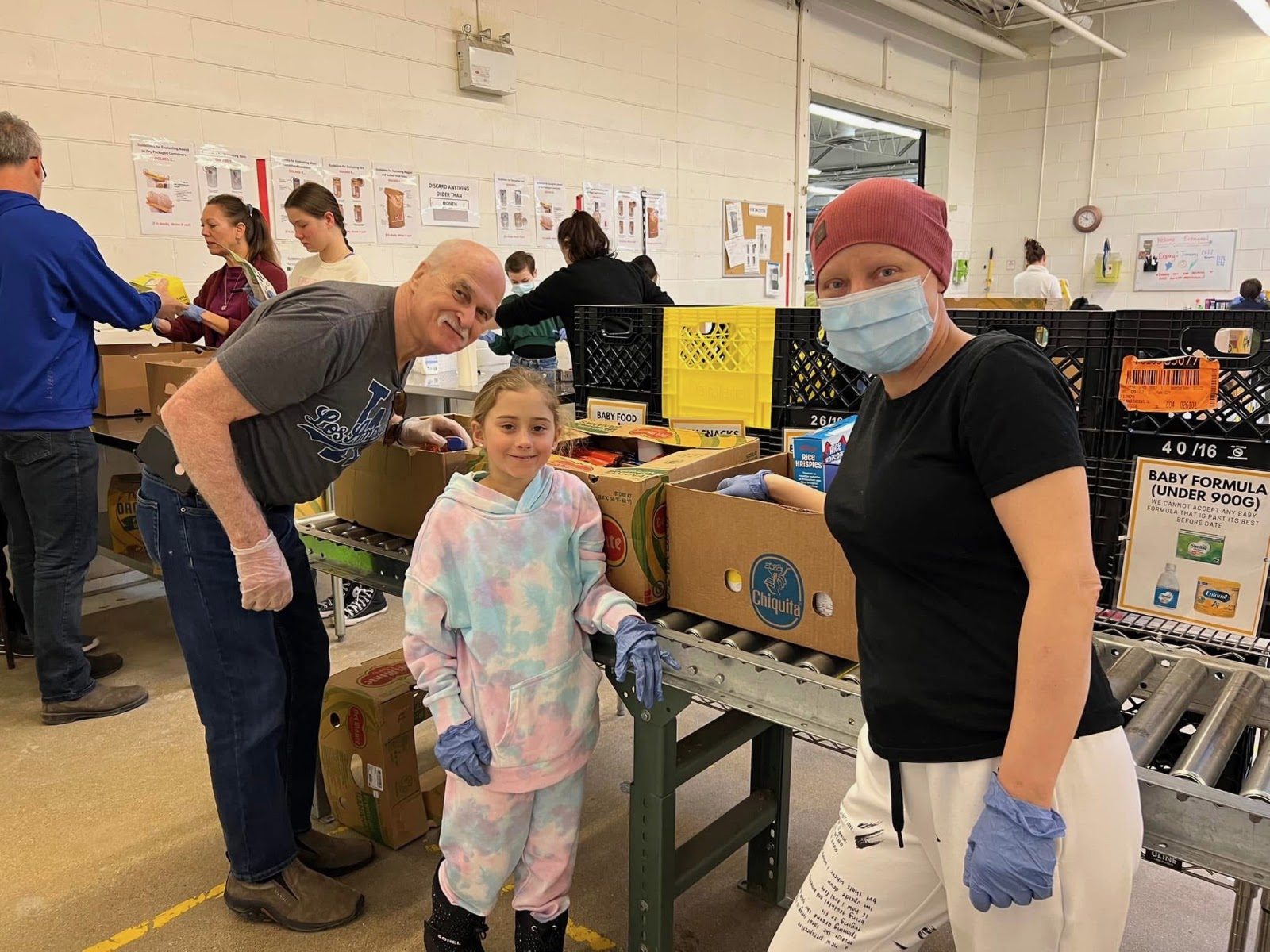 Laura volunteering with family, packing food boxes in a warehouse