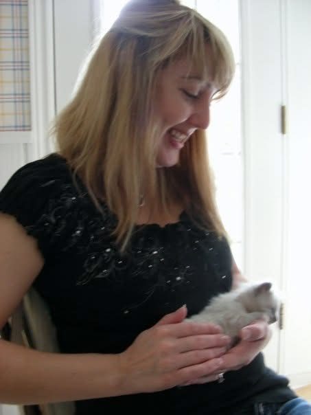 Laura smiling as she holds a tiny kitten