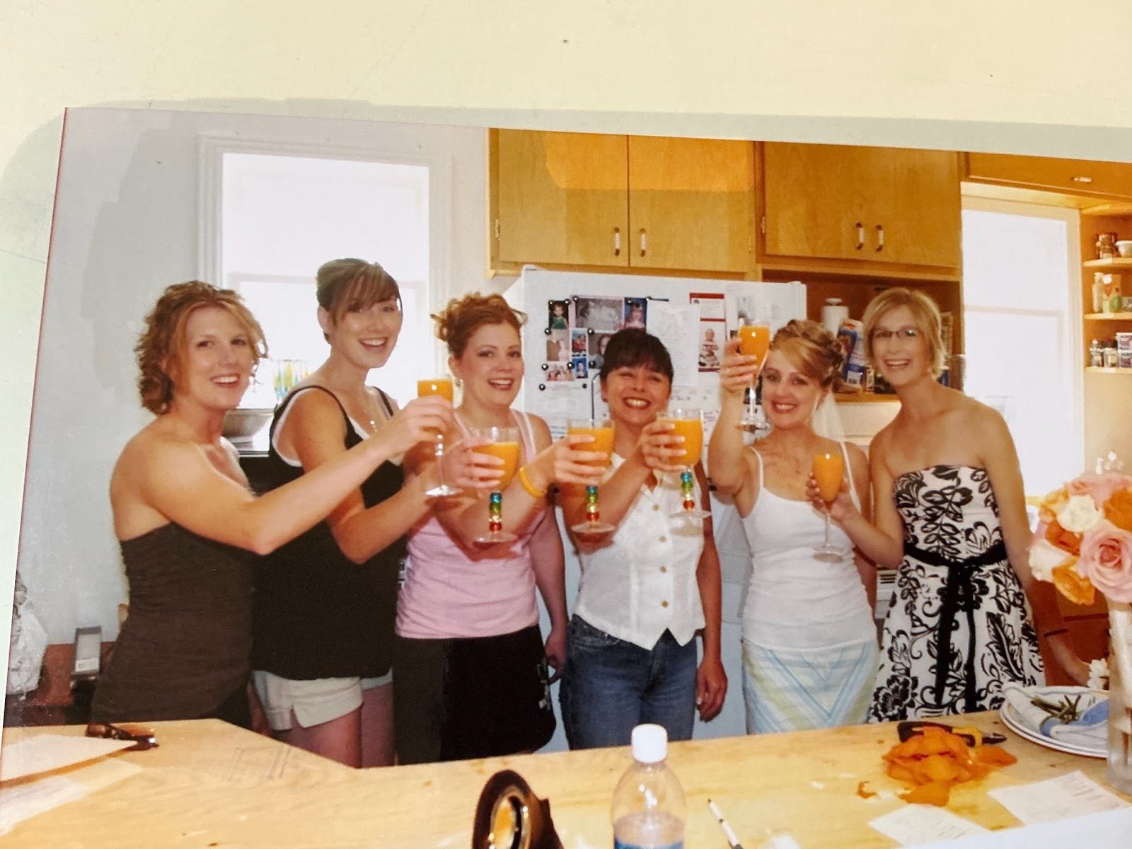 Laura and friends raising a toast in a kitchen on her wedding day