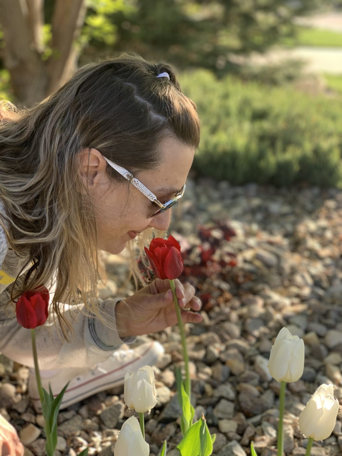 Laura leaning down to smell a red tulip